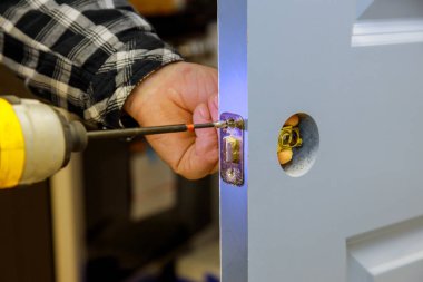 Tamirci eve kapı kilidi takmak için matkap kullanıyor.