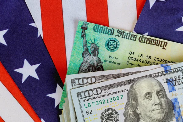 Stimulus Economic tax return Check and Us 100 $bills currency with Us flag — стокове фото