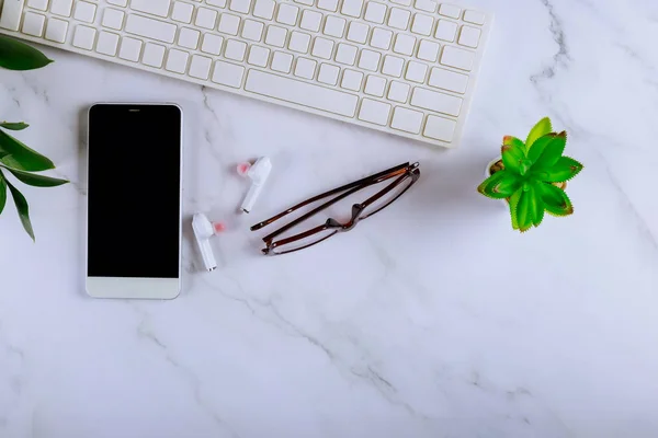 Espacio de trabajo de escritorio en el ordenador gafas de teclado smartphone auriculares inalámbricos — Foto de Stock