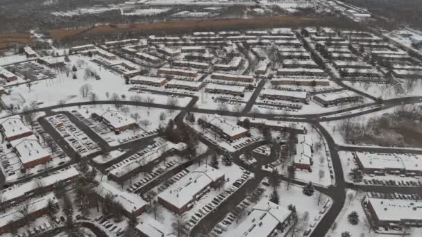 Aerial view flying over cnow covered town street and houses during snowfall — Stock video