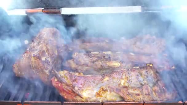 Pork bbq ribs on smoker grill with smoke on charcoal grilling in fire bacon outside, picnics concept. — Stockvideo