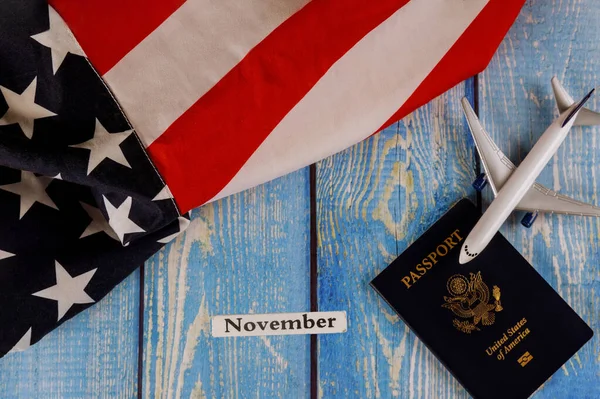 November month of calendar year, travel tourism, emigration the USA American national flag with U.S. passport and passenger model plane airplane