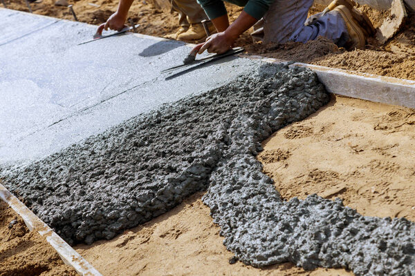Строители укладывают бетономешалку с бетономешалкой на тротуаре
