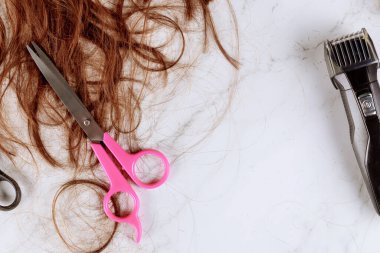 Kahverengi saçlı ve kuaför makasıyla budanmış elektrikli saç makası.