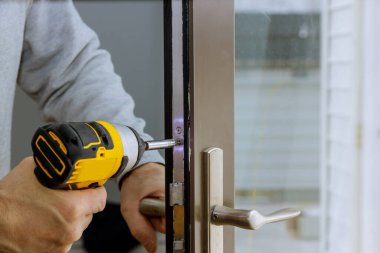 Yeni kapı kilidi montajındaki çilingir tornavidayı tutuyor