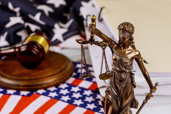 Justice holding the scales of justice with unfinished documents on law office table on American flag, symbol of law legal office