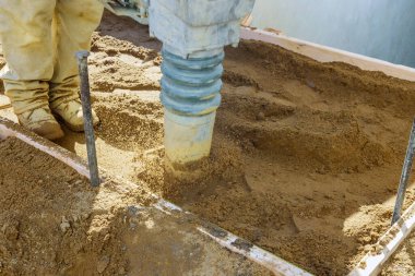 Kaldırım boyunca inşaat sürecinde kum zemininde zıplayan çekiç titreşimi