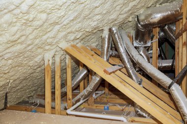 Yalıtım malzemesi ve boru ısıtma sistemiyle izole edilmiş çatı katı kirişleri olan bir bina.