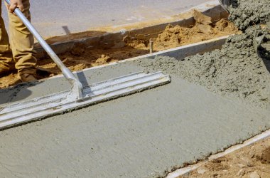 Çimento ve çakıl işçileriyle inşaat işleri el arabası ile beton işlerinde kaldırım için çimento döker.
