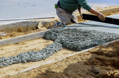 İnşaat işçileri kaldırıma beton karıştırıcı döşüyorlar.