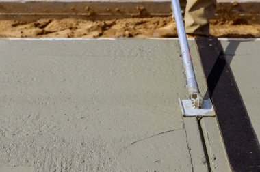 İnşaat işçileri kaldırıma beton karıştırıcı döşüyorlar.