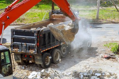 Kazı kamyonu inşaat atığını güçlendirilmiş beton geri dönüşüm çöpüne yüklüyor.