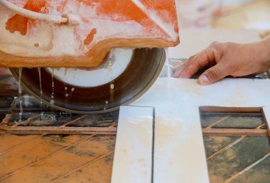 Yerdeki fayansları kesmek için testereyi kullanan bir işçi