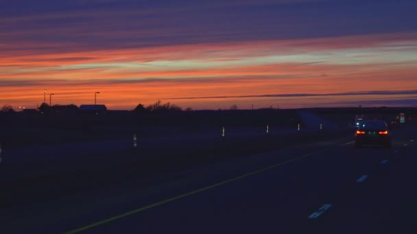 Colorida luz de tráfico nocturno ocupado en la carretera en EE.UU. durante una maravillosa puesta de sol — Vídeos de Stock