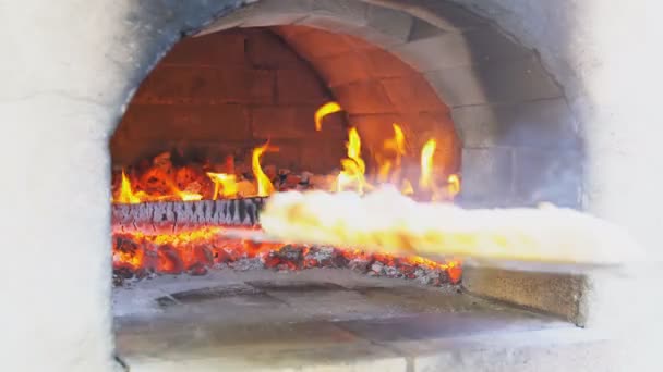 Достать вкусную пиццу из духовки в дровяной печи — стоковое видео