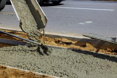 İşçi inşaat kamyonu karıştırıcısı kaldırım için beton döküyor