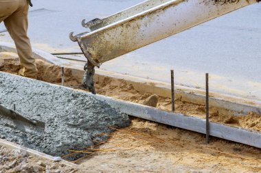 Sanayi işçileri güçlendirilmiş çimento kaldırımlarına taze beton döküyorlar.