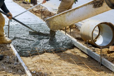 Beton kamyonu karıştırıcısı güçlendirilmiş beton kaldırıma taze beton döküyor.