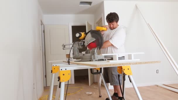 Worker cuts wood baseboard on the power miter saw — Stock Video