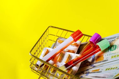 Sağlık giderleri, ABD parasıyla ilaç kapsülündeki virüs gribi enfeksiyonlarının taranması için kan örnekleri içeren tıbbi test tüpleri.
