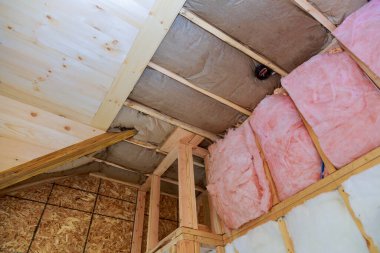 Tavan arası yalıtımı kısmen yalıtılmış. Pembe fiberglas bariyer katmanlarını kaplıyor.
