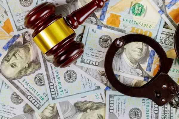 United States dollars bills cash on wooden judge gavel and handcuffs, legal justice desk