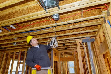 Elektrikçi yeni ev inşaatına elektrik kablosu yerleştiriyor