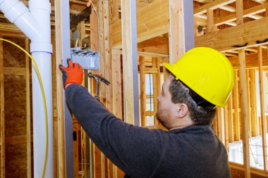 Elektrikçinin elleri yeni eve elektrik prizi takıyor.