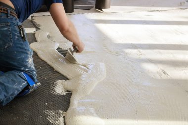 Beton zemindeki fayanslara hazırlanın. Teknisyenler beton zemine troweling yapışkanı ile çimento karıştırıyorlar.