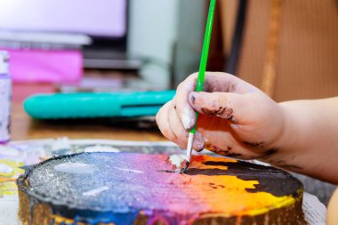 Bir kız ahşap üzerine çizimlerini yapmak için akrilik boya fırçasında kullanır.