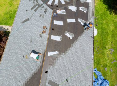Roofer asfalt kiremit çatı inşaatında çalışıyor.