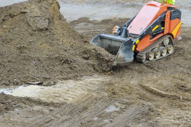 Toprak taşıma ekipmanları, sarı buldozer toprağı iterken kazma alanı.