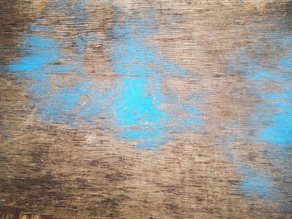 The texture of wooden boards with patches of blue paint. Background of wooden brown boards with patches of blue spread.