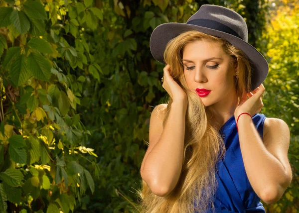 Beautiful girl with long hair in a hat and blue dress on a backg — Stock Photo, Image