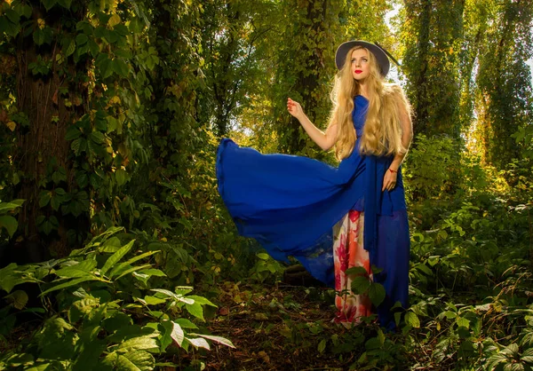 帽子と青いドレスの秋でポーズをとるには長い髪を持つ少女 fo — ストック写真