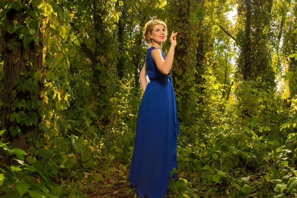 Belle fille dans une robe bleue posant dans la forêt — Photo