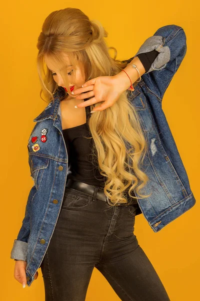 Beautiful blonde with long hair in a denim jacket posing — Stock Photo, Image