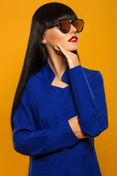 Chica con el pelo largo negro en un traje azul y gafas de sol posando — Foto de Stock