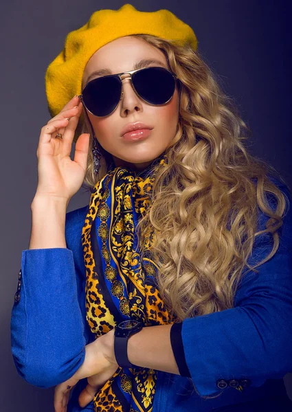 Nahaufnahme. ein Mädchen mit gelber Baskenmütze und Sonnenbrille posiert — Stockfoto