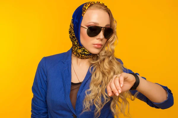 Blondin i en blå halsduk och en jacka i solglasögon tittar på th — Stockfoto