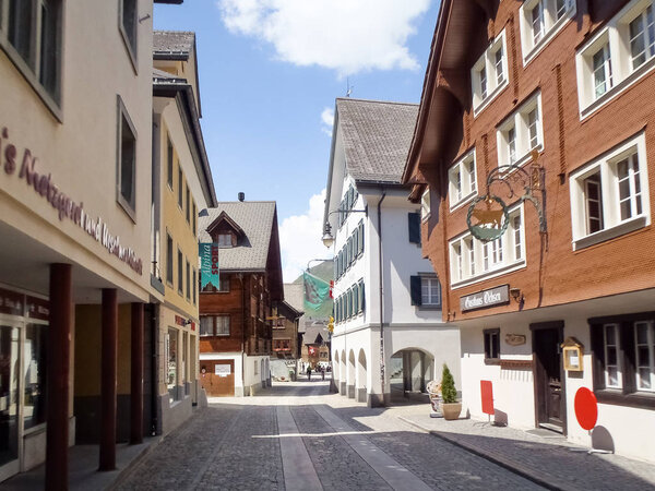 Andermatt, Switzerland - June 4, 2015: Canton Uri. Street crossing the village of Andermatt. Frame the typical mountain houses.