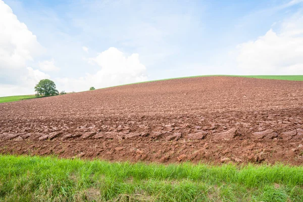 Un campo arado con tierra roja —  Fotos de Stock