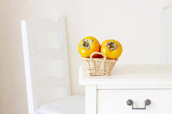 Kaki Fruit Rieten Mand Houten Tafel Stoel Achtergrond — Stockfoto