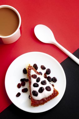 Limonlu kahvaltı, yoğurtlu elmalı pasta, sütlü yabanmersinli kahve fincanı ve kırmızı ve siyah arka planda kaşık.