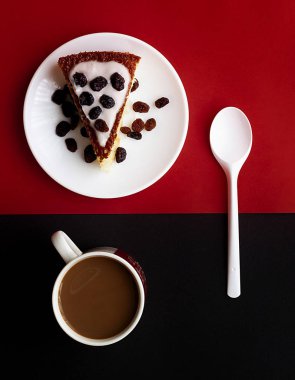 Limonlu kahvaltı, yoğurtlu elmalı pasta, sütlü yabanmersinli kahve fincanı ve kırmızı ve siyah arka planda kaşık.