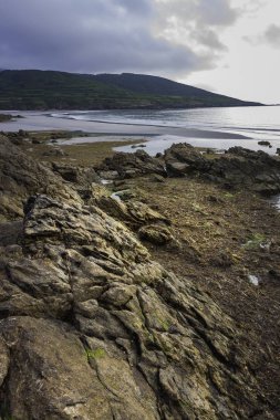 Sahilin kıyısındaki kayalar İspanya 'nın kuzeyindeki güneşin batışıyla aydınlanıyor.