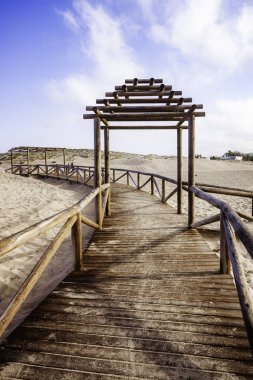Sahile giden ahşap pist ve bulutlu mavi gökyüzü.