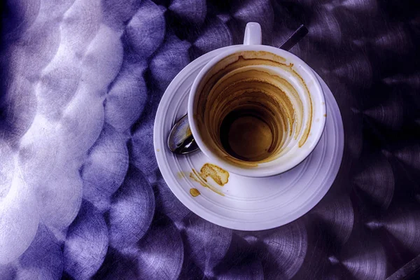 EMPTY COFFEE CUP WITH OILS ON RESTAURANT METAL TABLE