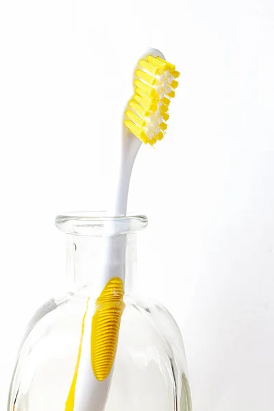 TOOTHBRUSH IN GLASS BOTTLE ON WHITE BACKGROUND. MOUTH HYGIENE Stock Picture
