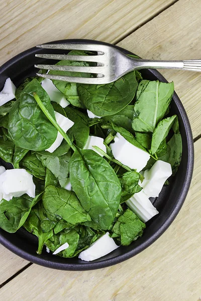 Beyaz peynirli ve çatallı yeşil ıspanak salatası.